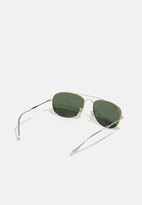 Ochelari de soare metalici aurii cu lentile verzi, formă ovală, cu brațe subțiri, vârfuri de urechi din plastic transparent și detalii de design minimaliste.