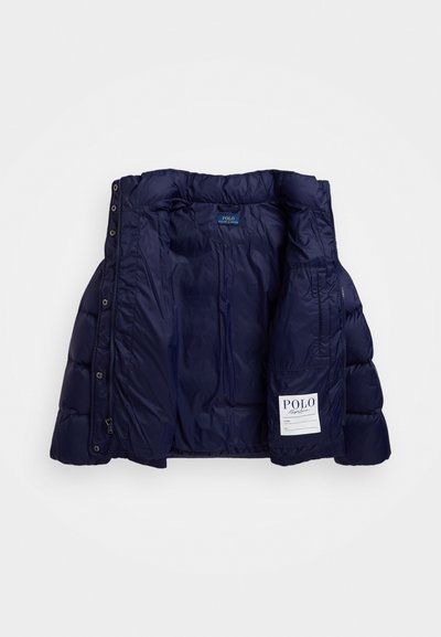 Navy blue puffer jacket interior featuring quilted texture, snap buttons, and a label with "POLO" and space for a name. Soft fabric.