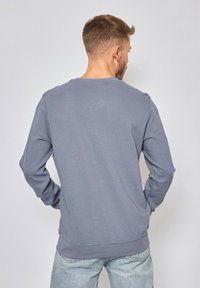 Sweatshirt gris à manches longues avec un design côtelé texturé, col rond et poignets ajustés. Tissu lisse. Vue arrière affichée.
