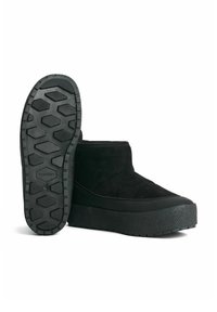 Svarta mocka ankelskor med en texturerad gummisula, med en lätt upphöjd plattform och sydda detaljer på ovansidan.