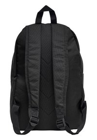 Mochila negra con correas de hombro acolchadas, tejido texturizado y un asa en la parte superior. La parte trasera presenta un sutil patrón en forma de chevron.