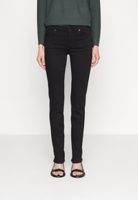 Black skinny jeans with a low rise, five pockets, and silver hardware. Made of denim with a smooth texture, featuring a classic design.