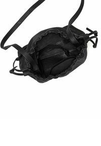 Sort læder skuldertaske med snorelukning åben for at vise inderside og justerbar rem på hvid baggrund.