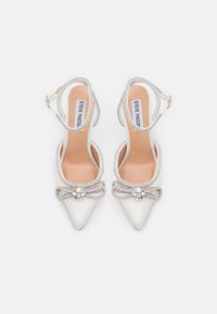 White satin pointed-toe heels with a silver bow and crystal accents. Slingback design with a textured strap and beige insole.