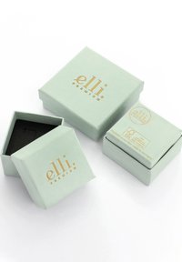 Lys grønne firkantede smykkebokse med mat finish og guldtekst. En boks er let åben og afslører et sort indre.