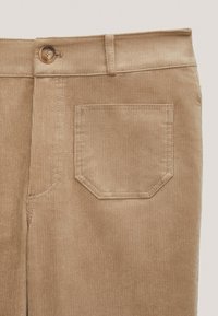 Bruna kordbyxor med rak design, med knäppning och en enda bakficka med en distinkt åttakantig form.