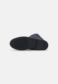 Chaussure supérieure texturée bleu marine avec une semelle en caoutchouc noire dotée d'une adhérence à motif. Détail de fermeture éclair sur le côté. Taille 37 marquée sur la semelle.