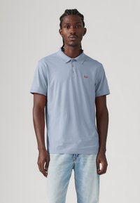 Light blue polo shirt made of cotton, featuring a collared neck, three-button placket, and a small Levi's logo on the chest.