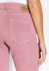 Vaqueros de denim rosa con un acabado texturizado, que cuentan con una pretina con un parche de logo y un bolsillo trasero con un detalle de costura sutil.