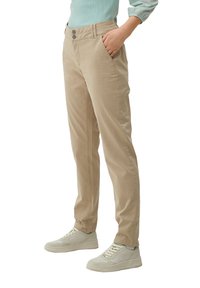 Beige, slim-fit byxor med två sidofickor, knappstängning och en mjuk textur, i kombination med ljusa sneakers.