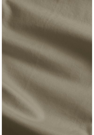 Beiger Stoff mit einer glatten, leicht glänzenden Textur; zeigt weiche Falten und sanftes Drapieren, das seine Flexibilität und Fließfähigkeit betont.