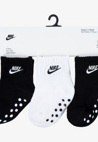 Three-pack of lightweight, non-slip socks in black and white. Each sock features elastic cuffs and small non-slip dots on the soles.
