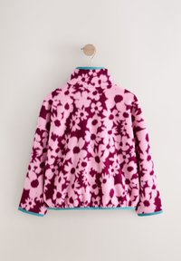 Rózsaszín polárdzseki sötétlila virágmintával; álló gallérral és türkiz szegéllyel a szegélyen és az ujjakon. Hátsó nézet.