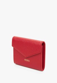 Czerwony skórzany portfel o fakturowanej powierzchni z klapką kopertową, złotym logo oraz kompaktowym, prostokątnym kształcie.