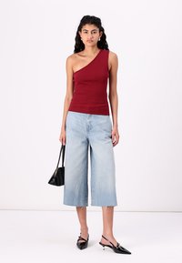 Burgundy one-shoulder ribbed tank top, light blue wide-leg jeans, black pointed-toe heels, and a small black handbag. Smooth textures.