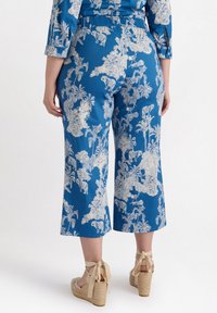 Blå korta byxor med ett blommönster och djurmönster i vitt; mjukt, lätt tyg; har en elastisk midja och vida ben.