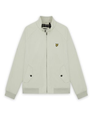 Lys beige glidelåsjakke med ståkrage, to knappede frontlommer, ribbestrikkede mansjetter, og en liten gul fuglelogo på venstre bryst.