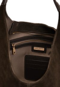 Suède handtas met een donkerbruine buitenkant, voorzien van een beige voering, meerdere met rits afgesloten compartimenten en een zwarte leren kaart houder binnenin.