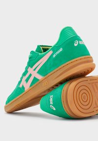 Rohelised sametist treeningjalatsid roosa aktsendiga, ümar nina, kummist tallaga ja kõrgendatud kontsaga. "ASICS" logo ja "SKYHAND" tekst kanna ja külje peal.