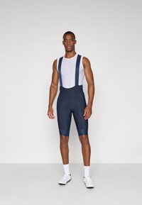 Pantalones cortos de ciclismo en azul marino, con una camiseta interior texturizada blanca, tirantes ajustables, asiento acolchado y diseño ajustado.