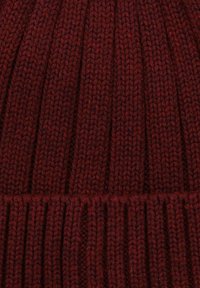 Czerwona dziana czapka z prążkowanym wzorem, z pionowymi liniami i grubym mankietem. Wykonana z miękkiej mieszanki wełny.