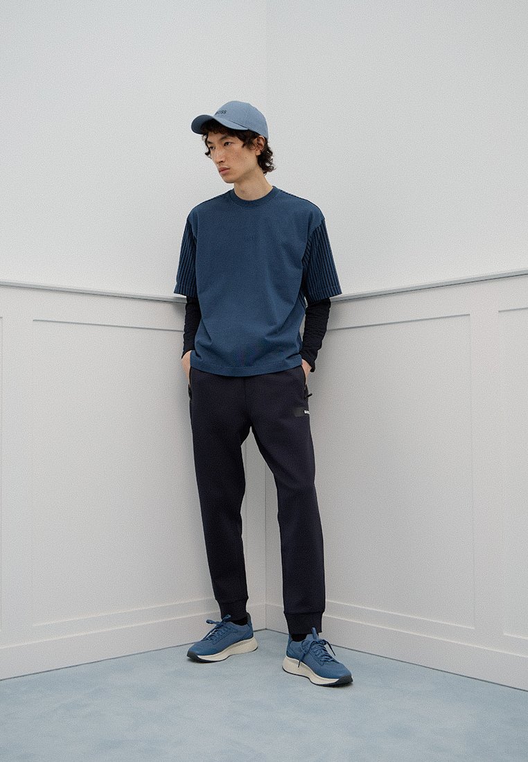 Korte mouwen navy t-shirt met geribbelde accenten, gecombineerd met navy joggingbroek en blauwe sneakers, aangevuld met een bijpassende pet.