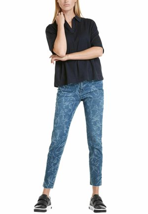 Námořnický krátký rukáv blůza v kombinaci s džínami se světle modrým vzorem. Černé tenisky s bílou podrážkou dotvářejí slavnostní vzhled.