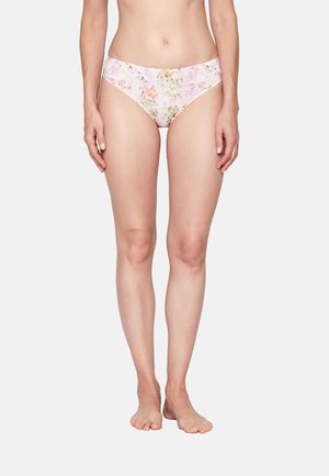 Woman standing barefoot wearing light pink floral patterned bikini-style underwear against white background.