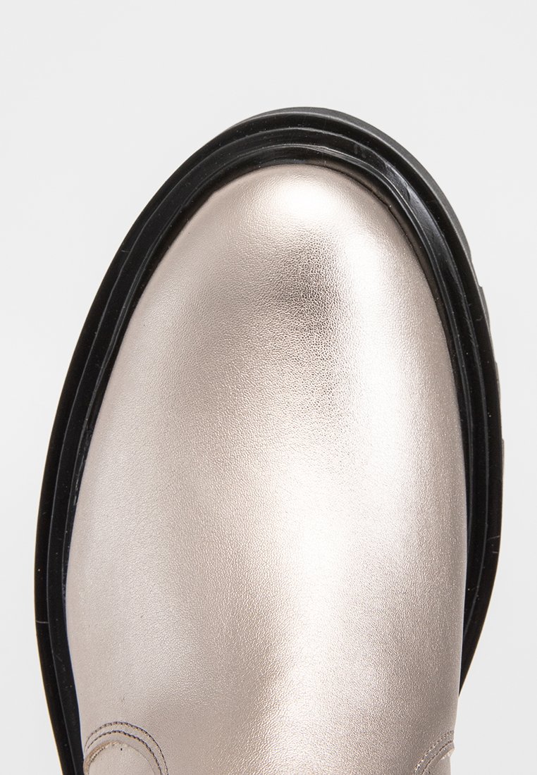 Metallisch silberner Schuh mit runder Zehenpartie, glatter Textur und schwarzer Gummisohle. Beinhaltet dezente Nähte entlang des Randes.