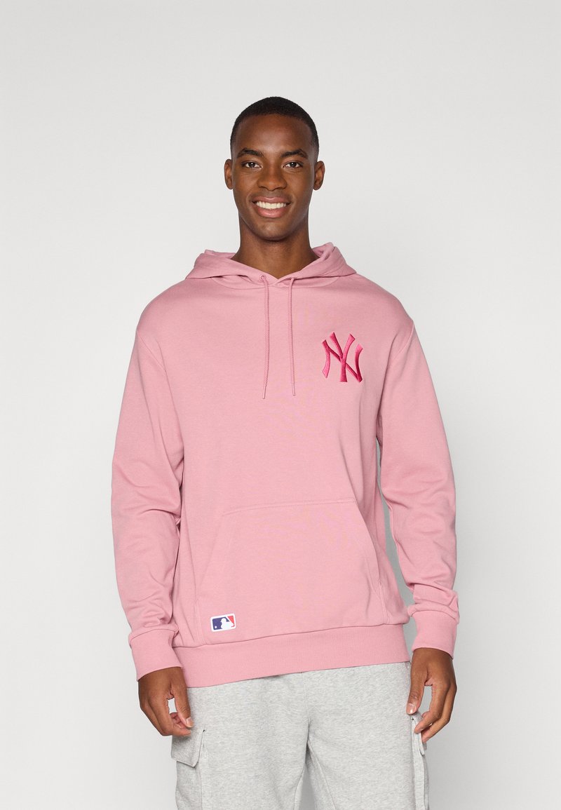 Haut à capuche rose avec une poche avant, présentant un logo brodé rose foncé sur la poitrine et un écusson MLB sur l'ourlet. Tissu doux, coupe décontractée.