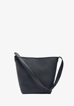 Czarna torebka na ramię ze skóry ziarnistej z regulowanym paskiem i minimalnym przeszyciem, w kształcie trapezu o szerokim wierzchu na białym tle.