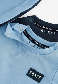 Drei T-Shirts in Hellblau und Marineblau, mit runden Halsausschnitten, Schulterknöpfen und einem schwarzen Logo-Tag, auf dem "BAKER by TED BAKER" steht.