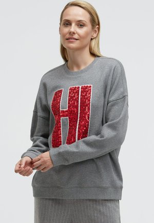 Grauer Pullover mit großem roten Pailletten- "HI"-Design auf der Vorderseite, mit rundem Ausschnitt und gerippten Bündchen.