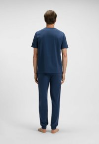 Navy blue loungewear-asu setti, joka sisältää lyhythihaisen crewneck-paidan ja vastaavat housut elastisilla hihansuilla, valmistettu pehmeästä kankaasta.