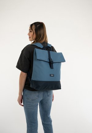 Blue and dark navy backpack with a fold-over flap and a single buckle closure, made from a smooth fabric. Adjustable shoulder straps.