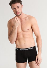 Boxer aderenti neri, con un design sagomato, dotati di un cinturino spesso contrassegnato da "G-STAR RAW" in lettere bianche. Tessuto morbido ed elastico.