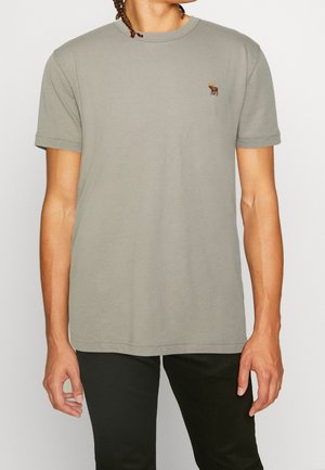 T-shirt grigia in cotone con scollo rotondo e maniche corte. Presenta un piccolo logo animale ricamato marrone sul petto a sinistra.