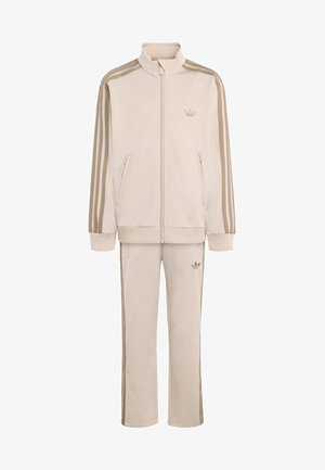 Beige Adidas træningssæt med lynlåstrøje, sidelommer og matchende bukser med tre brune striber langs ærmer og ben.