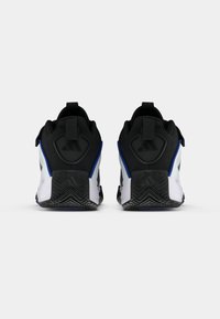 Černobílé sportovní boty s modrými akcenty, mají texturovaný svršek, polstrovaný límec a silnou gumovou podrážku se zigzagovým vzorem.