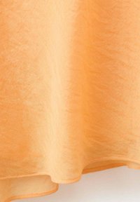 Tissu orange clair, semi-transparent avec une texture subtile, drapé doucement créant de doux plis et un ourlet arrondi.
