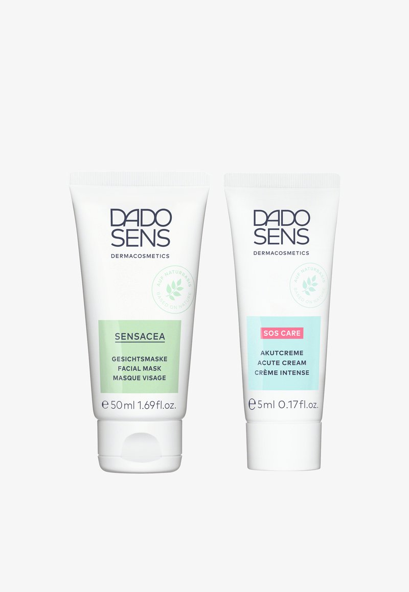 Two tubes of DADO SENS skincare products: a green 50ml facial mask and a blue 5ml acute cream, both with white caps and text.