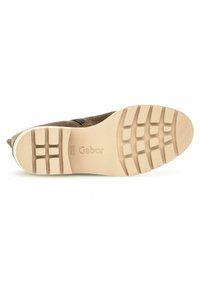 Brown suede shoe with a textured beige rubber sole, featuring a patterned grip design and embossed logo.