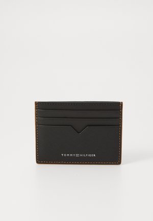 Black leather cardholder with orange stitching, featuring card slots and a subtle logo detail on the front. Rectangular shape, textured surface.