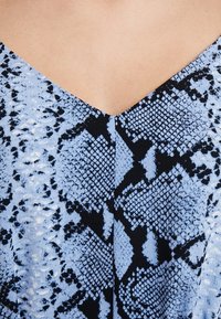 V-neck dress featuring a blue and black snake print pattern. Smooth texture with contrasting dark accents throughout the fabric.