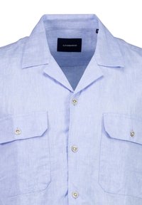 Vaaleansininen pellavapaita, jossa on kaulus, kaksi etutaskua ja hopeanvärisiä nappeja. Paita on valmistettu teksturoidusta kankaasta ja siinä on brändilappu kauluksessa.