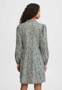 Abito a fantasia floreale in blu e beige, con lunghe maniche a sbuffo, busto attillato e vita cintrata, che arriva fino a metà coscia.