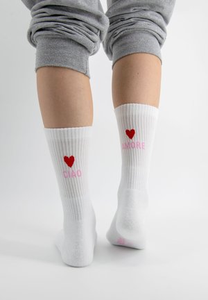 Białe skarpetki w prążki z różowym i czerwonym napisem. Zawierają serca oraz słowa „CIAO” i „AMORE”. Miękki materiał, długość do kostki.