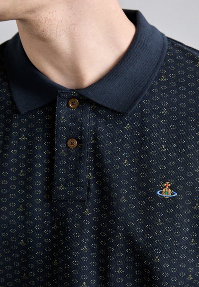 Marineblaues Poloshirt mit einem strukturierten Muster aus kleinen Punkten; verfügt über einen geknöpften Kragen und ein kleines gesticktes Design eines Bootes.