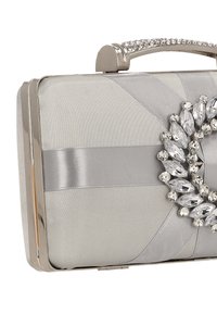 Ezüst szatén borítéktáska ékszeres díszítéssel, fém szegéllyel és texturált fogantyúval. Átlós szalagdíszítéssel és elegáns téglalap alakú kialakítással.