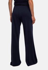 Marineblauwe wijde broek gemaakt van een soepel materiaal, met een comfortabele hoge tailleband en een ontspannen silhouet, afgewerkt met een nette zoom.